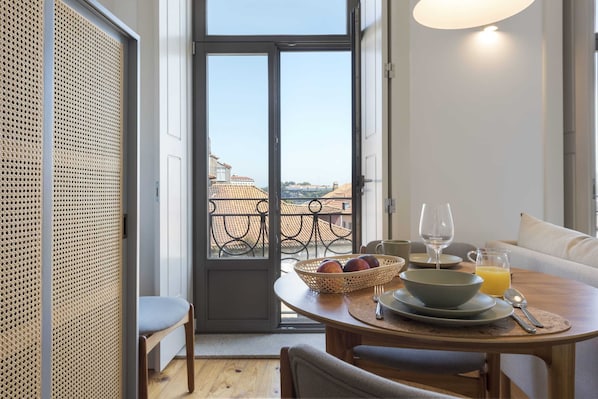 A dining area with a table set for breakfast, including a bowl, plates, and a glass of orange juice.