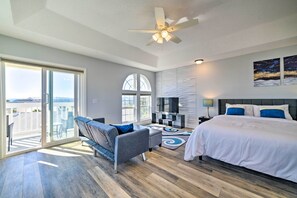 Un dormitorio moderno con cama, sofá, televisión y balcón con vistas.