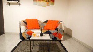 A modern living room with a sofa, a coffee table, and a small shelf with a speaker. - Agora Holiday House (Palazzolo Acreide)