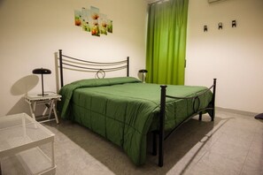 A room with a single bed, a small table, a lamp, and a green curtain.