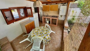 A compact kitchen with a dining area, a ceiling fan, and a view of the garden. - Blue Med Scooby, Palinuro, Cilento (Palinuro)