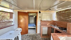A compact kitchen with a gas stove, a sink, and a small dining area with a table and chairs. - Blue Med Bambi, Palinuro, Cilento (Palinuro)