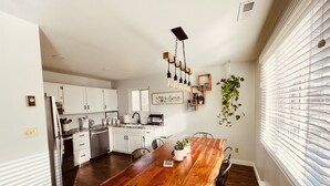 A modern kitchen with white cabinets, a wooden dining table, and a hanging plant. - The Apartment Suite! Private Hot Tub w/ Mountain Views (Colorado Springs)
