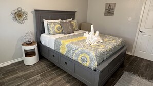 Ein ordentlich eingerichtetes Schlafzimmer mit einem Bett, Nachttischen und einem an der Wand hängenden Kunstwerk.