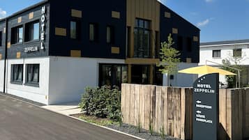 Un hotel modern amb façana negra i blanca, una zona de recepció i un senyal que indica una àrea d'aparcament per a clients.