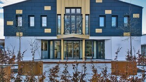 Un edificio moderno con fachada simétrica, ventanas amplias y una entrada central con puertas de cristal.