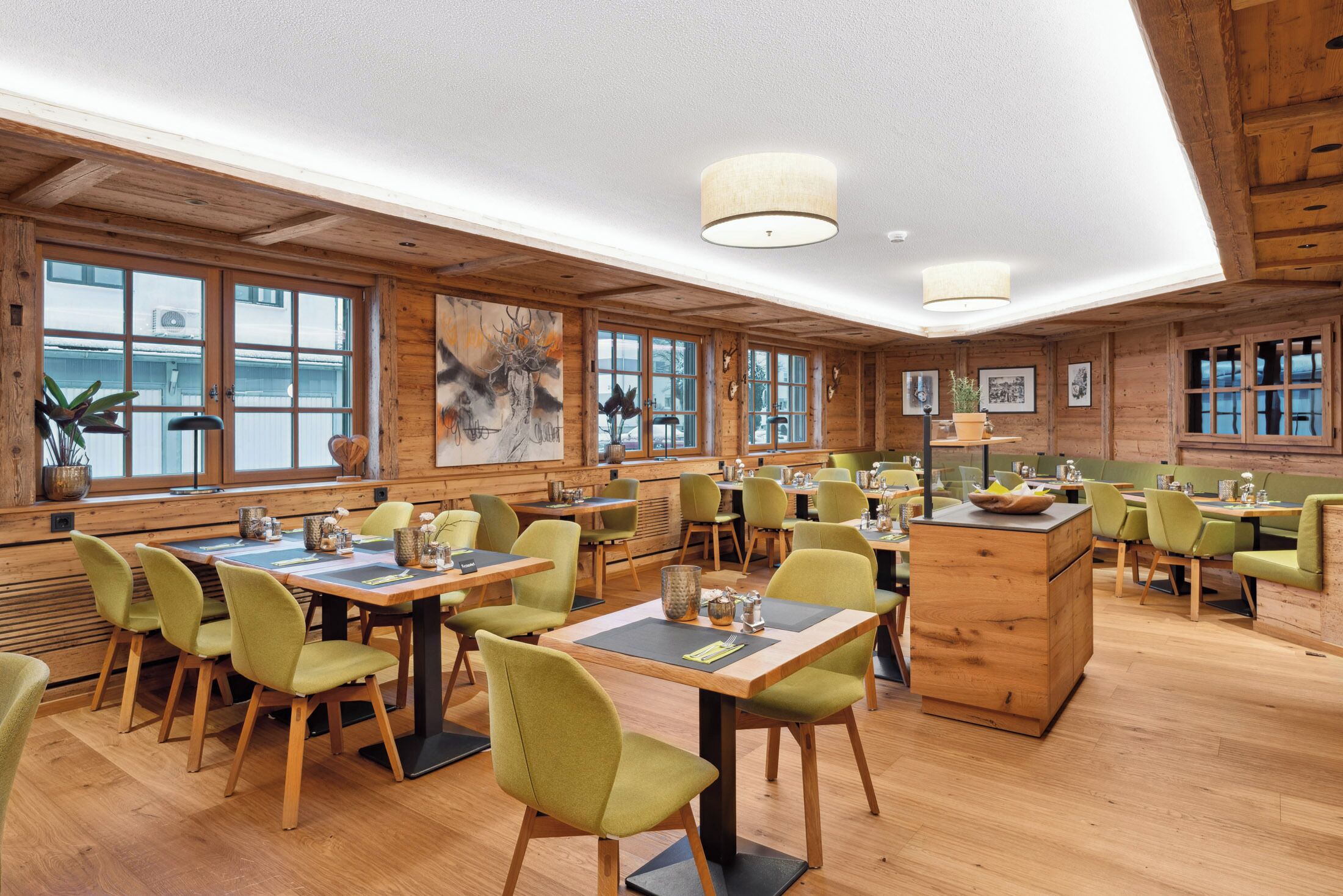 A spacious restaurant with wooden walls and large windows, featuring multiple tables and chairs.