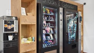 A vending machine area with snacks and drinks, a coffee machine, and a refrigerator.