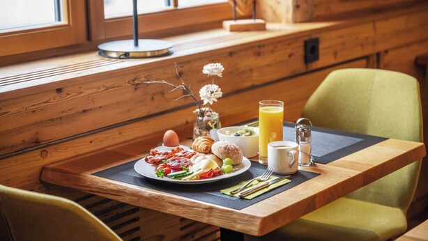 Una mesa de desayuno con un plato de comida, un vaso de jugo de naranja y una taza.