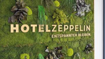 A hotel named HOTELZEPPELIN with a green, mossy wall and various plants.