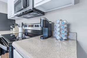 A kitchen with a coffee maker, a microwave, and a container of coffee pods.