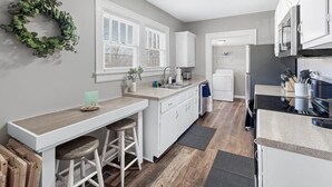 A modern kitchen with white cabinetry, a bar area with stools, a built-in oven, and a refrigerator. - Red Bud (Chattanooga)