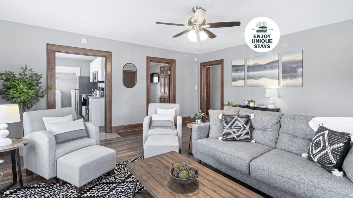 Un salon moderne avec un canapé gris, un fauteuil blanc et une table basse en bois sur laquelle est posé un bol décoratif.