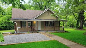 A single-story house with a front porch, a small front yard with a gravel area, and a well-maintained lawn. - Red Bud (Chattanooga)