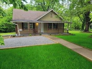 A single-story house with a front porch, a small front yard with a gravel area, and a well-maintained lawn.