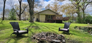 A house with a porch, two wicker chairs, and a pile of firewood.