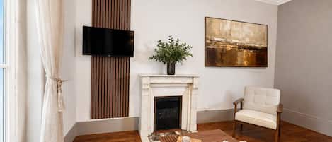 Una sala de estar con chimenea, televisor montado en la pared, sofá y mesa de centro con bandeja.