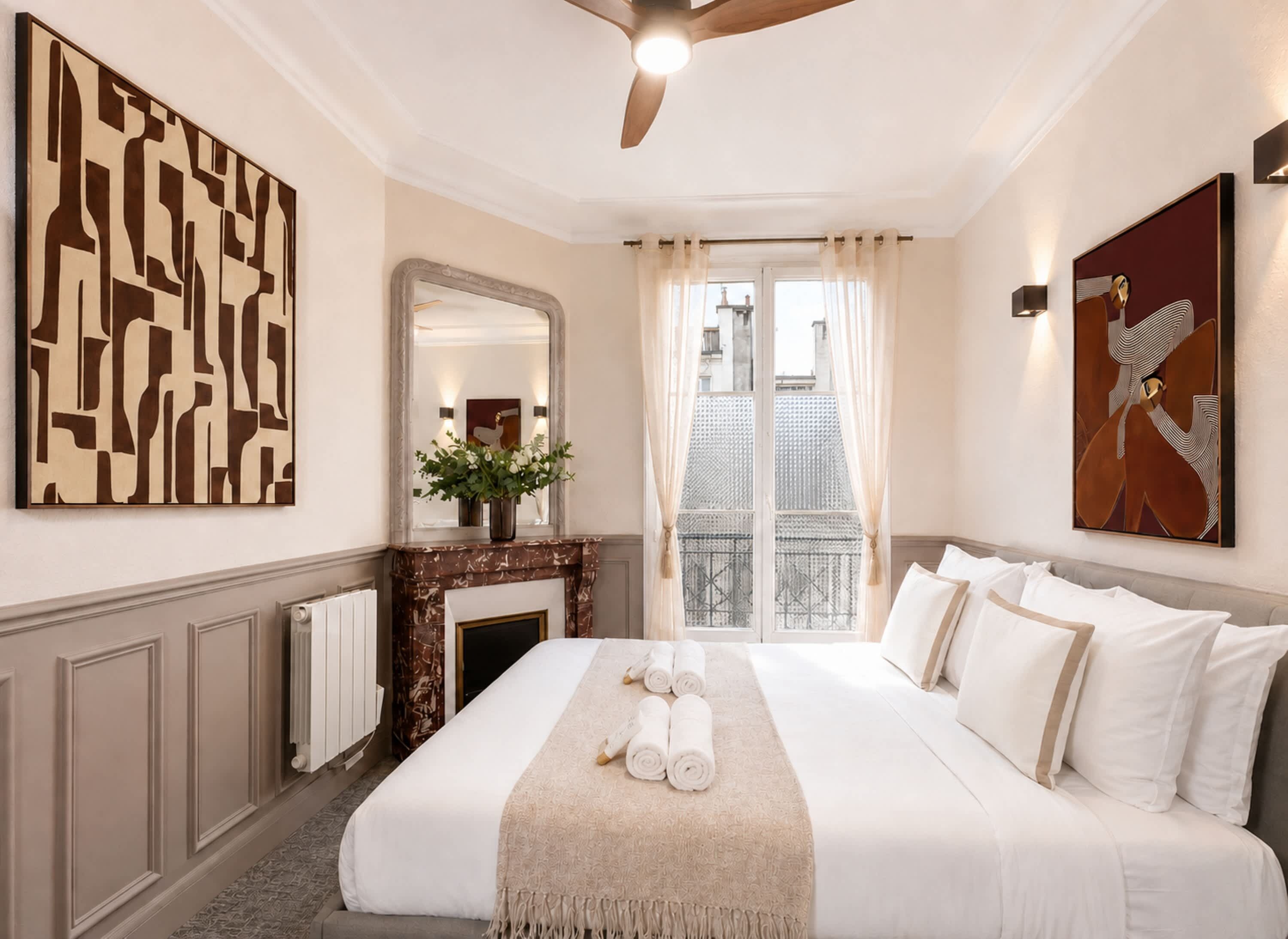 Une chambre d’hôtel dotée d’un grand lit, d’une cheminée, d’un miroir et d’œuvres d’art accrochées aux murs.