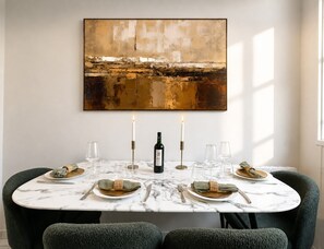 A dining table with a marble top, two candles, and a bottle of wine, set for four. - Charming flat with lift - Eiffel Tower (Paris)