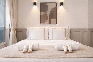 A hotel room with a large bed, two wall-mounted lights, a framed abstract artwork, and a window with curtains.