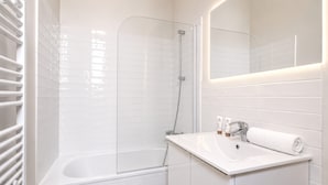 A modern bathroom with a glass-enclosed shower, a white sink, and a mirror above it.