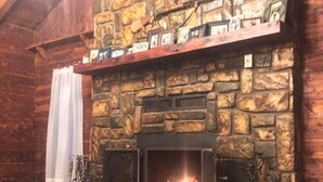 A stone fireplace with a mantel displaying framed photos and a decorative wreath.