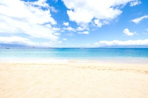 Une plage avec un ciel dégagé et une mer calme.
