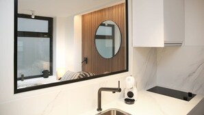 Un baño moderno con un espejo grande, un lavamanos, un calentador de toallas y una ventana con persianas.
