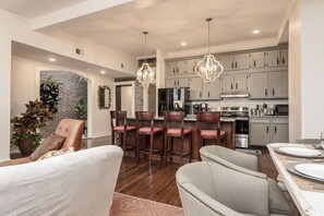 A modern kitchen with grey cabinets, stainless steel appliances, and a brick accent wall.