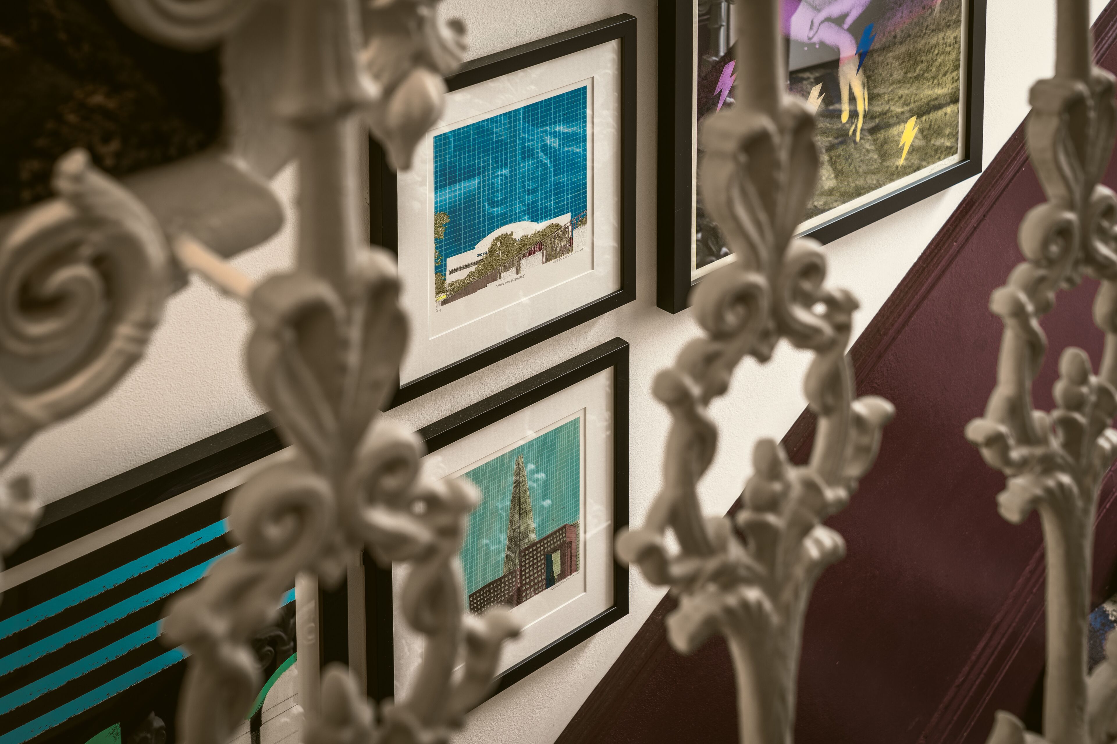 A wall with framed architectural drawings and decorative metalwork.