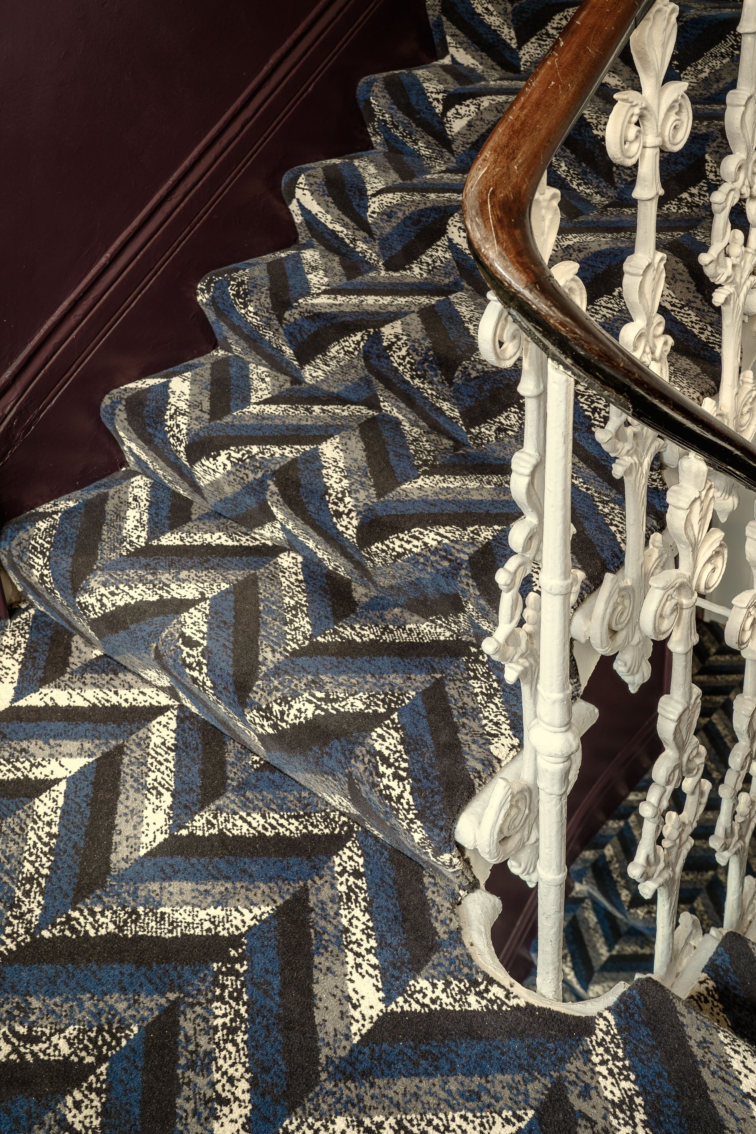 A staircase with a patterned carpet and white ornate railings.
