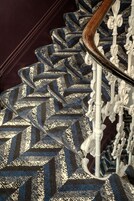 Eine Treppe mit einem gemusterten Teppich und weißen, verzierten Geländern.