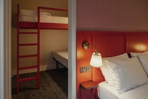 Ein Zimmer mit Etagenbetten, einer Leiter, einem Nachttisch mit Lampe und einer Steckdose.