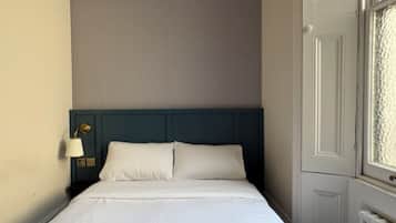 Une chambre d’hôtel avec un lit, une table de chevet, une lampe et une fenêtre.