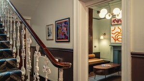 Un escalier orné de balustrades blanches et doté d’une main courante en bois foncé, menant à une pièce où se trouvent un canapé et une petite table.