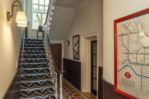 Una escalera con alfombra estampada, una lámpara de pared y un mapa del metro.