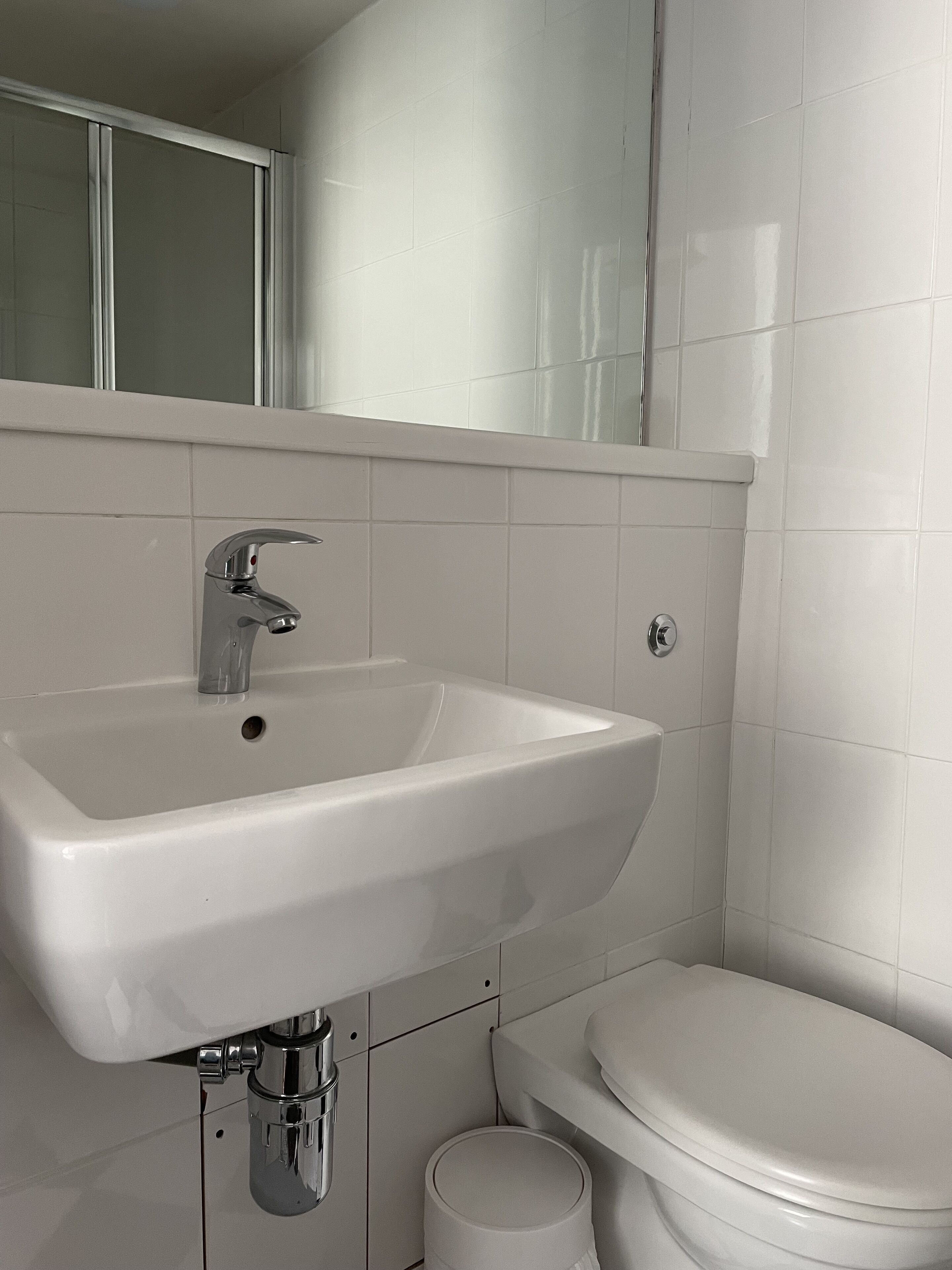 A bathroom with a white sink, chrome faucet, and a toilet.