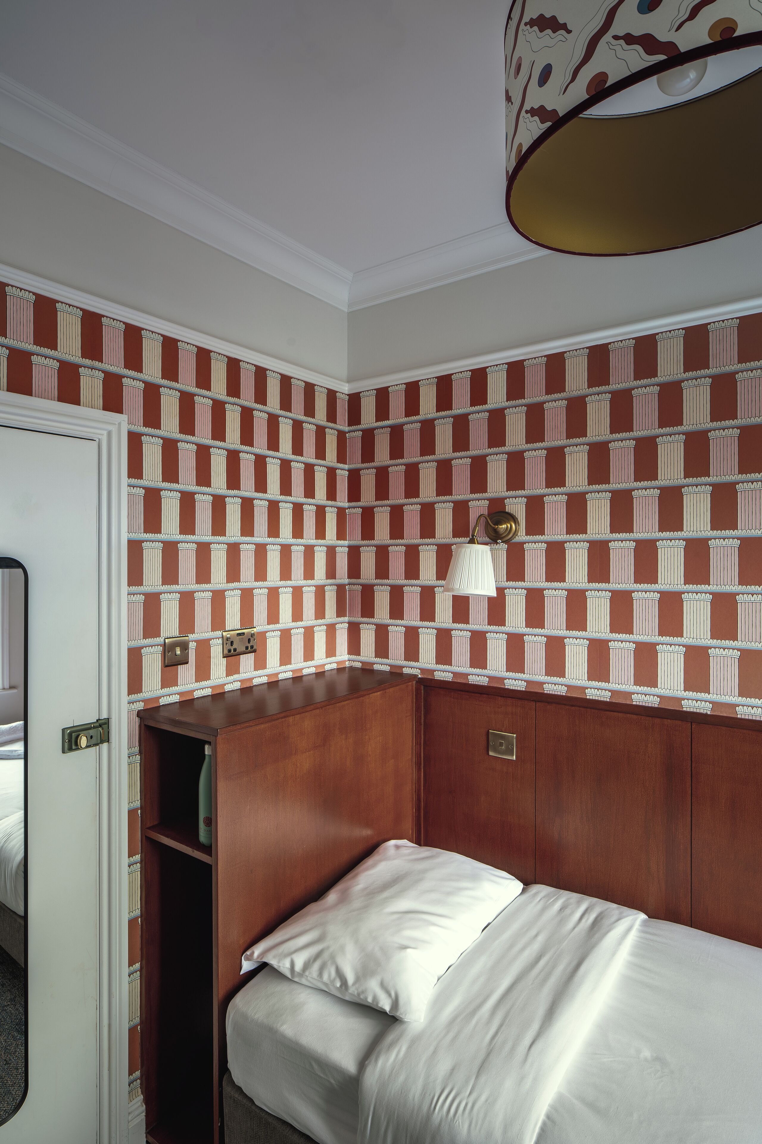 Una habitación con cama, armario y papel tapiz estampado.