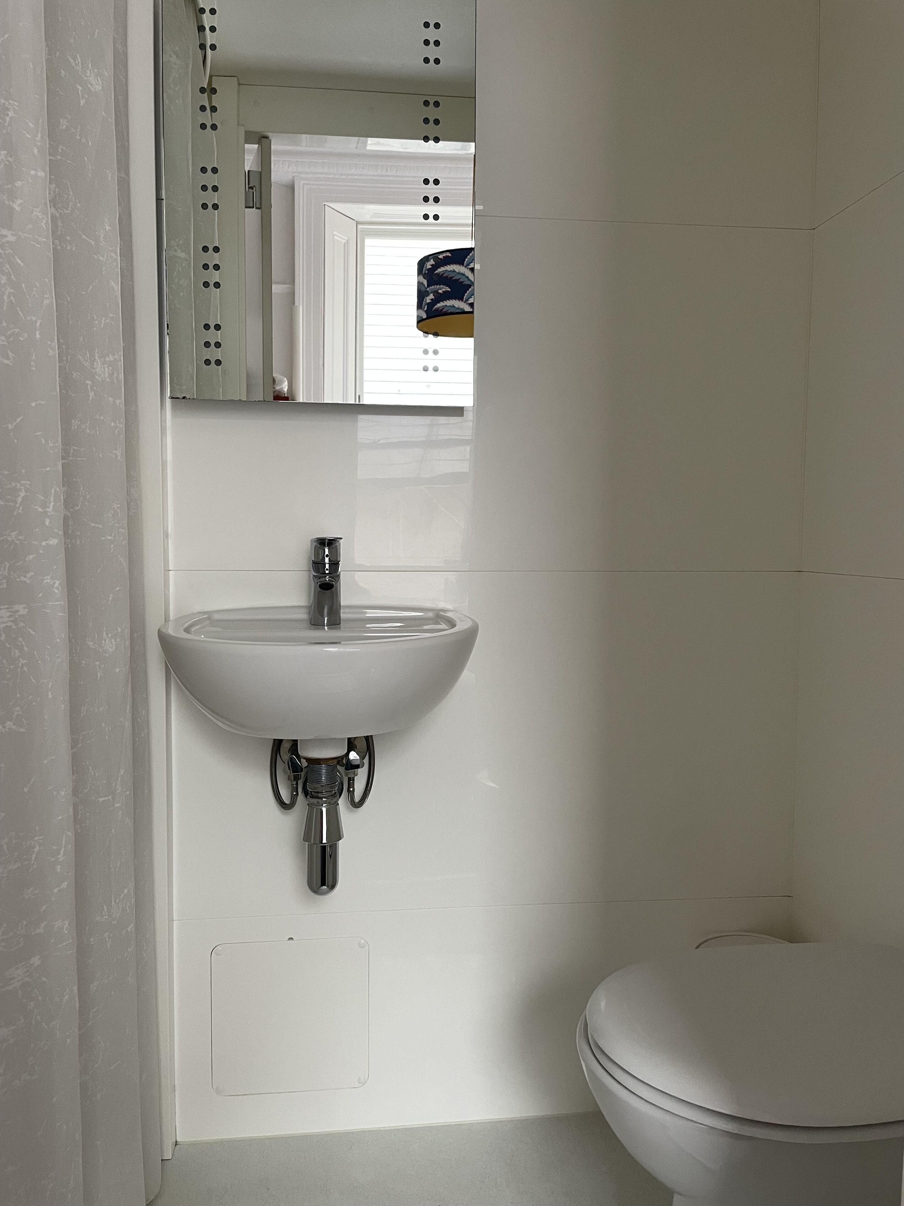 A bathroom with a white sink, a mirror, and a toilet.