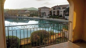 A balcony with a view of a lake and buildings. - Magnificent lake view at Golf de Pont-Royal (Mallemort)