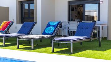 Een buitenzwembad, een verwarmd zwembad, ligstoelen bij het zwembad