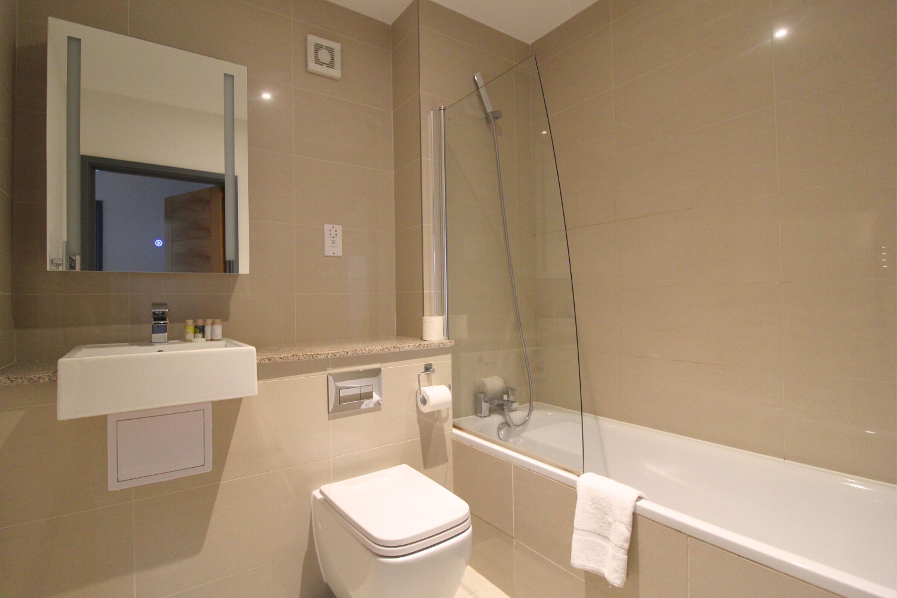 A modern bathroom with a glass-enclosed shower, a white sink, and a toilet.