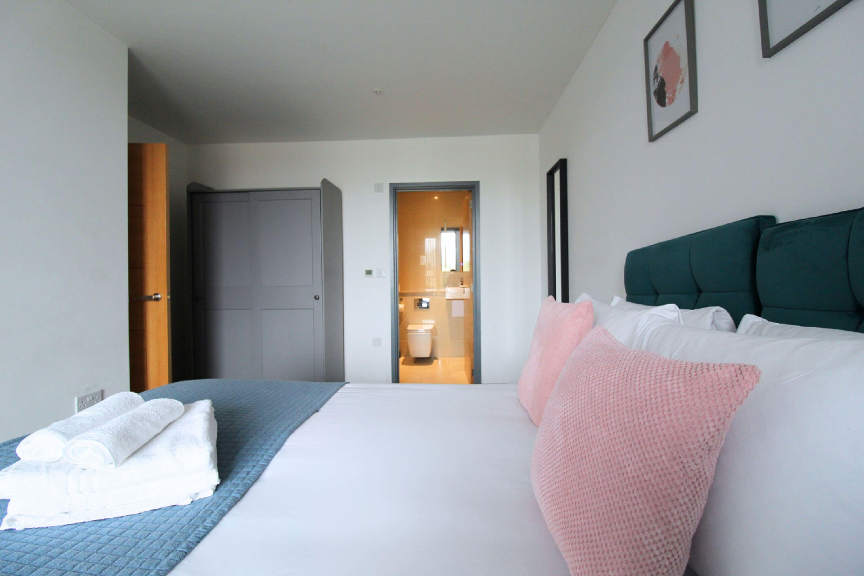 Une chambre d’hôtel avec un lit, des oreillers, une couvre-lit matelassée bleue et un mur blanc.