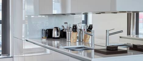 A modern kitchen with white cabinetry, a stainless steel sink, and a wooden floor.