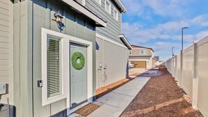 A residential building with a door, a wreath, and a pathway leading to another house.