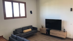 Ein modernes Wohnzimmer mit einem Ecksofa, einem Flachbildfernseher und einer Holzkommode.