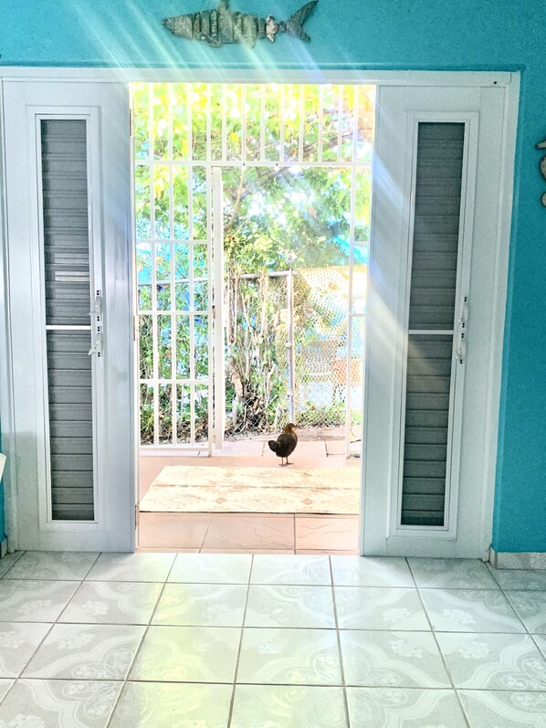 A room with a tiled floor, a door leading outside, and a bird on the patio.