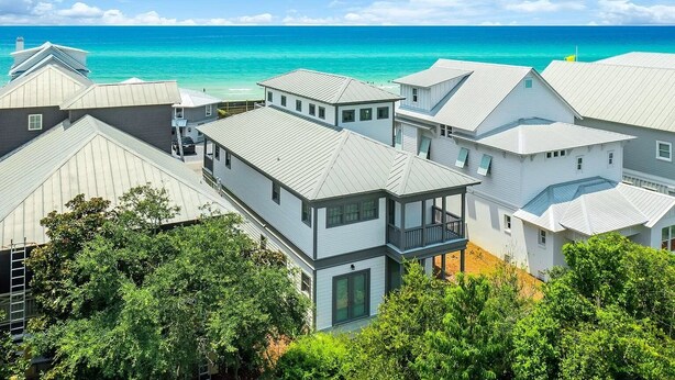 A coastal residential area with houses featuring gabled roofs and a view of the turquoise sea.