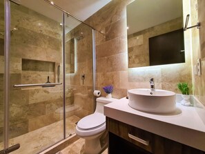 A modern bathroom with a glass-enclosed shower, a white toilet, and a vanity with a sink.