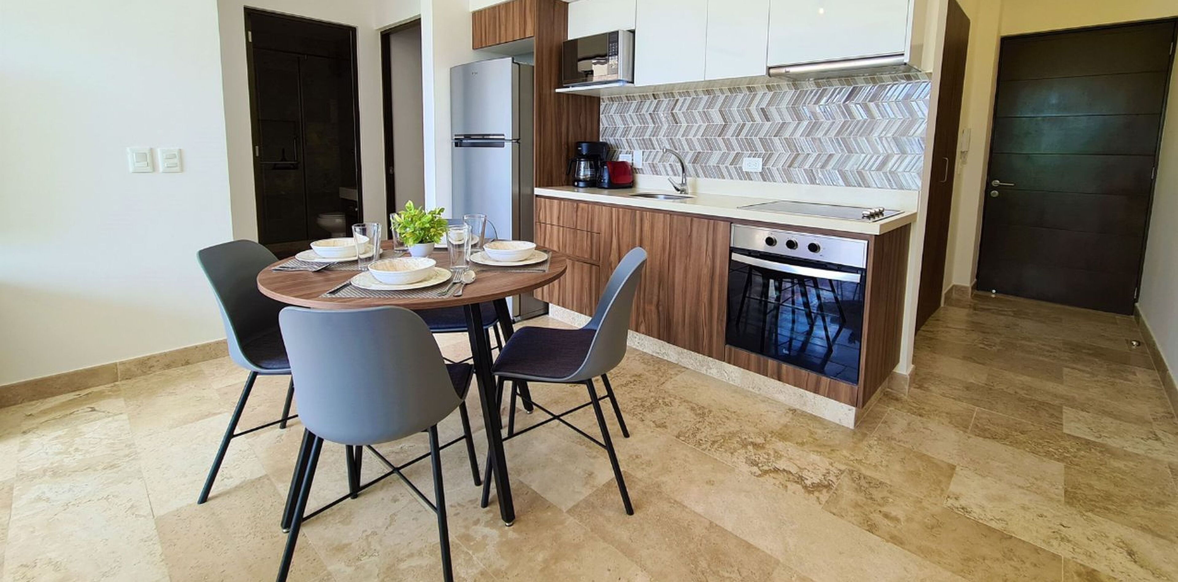 Une cuisine compacte avec un coin repas, comprenant une table ronde avec des chaises, un réfrigérateur, une cuisinière et un four à micro-ondes.
